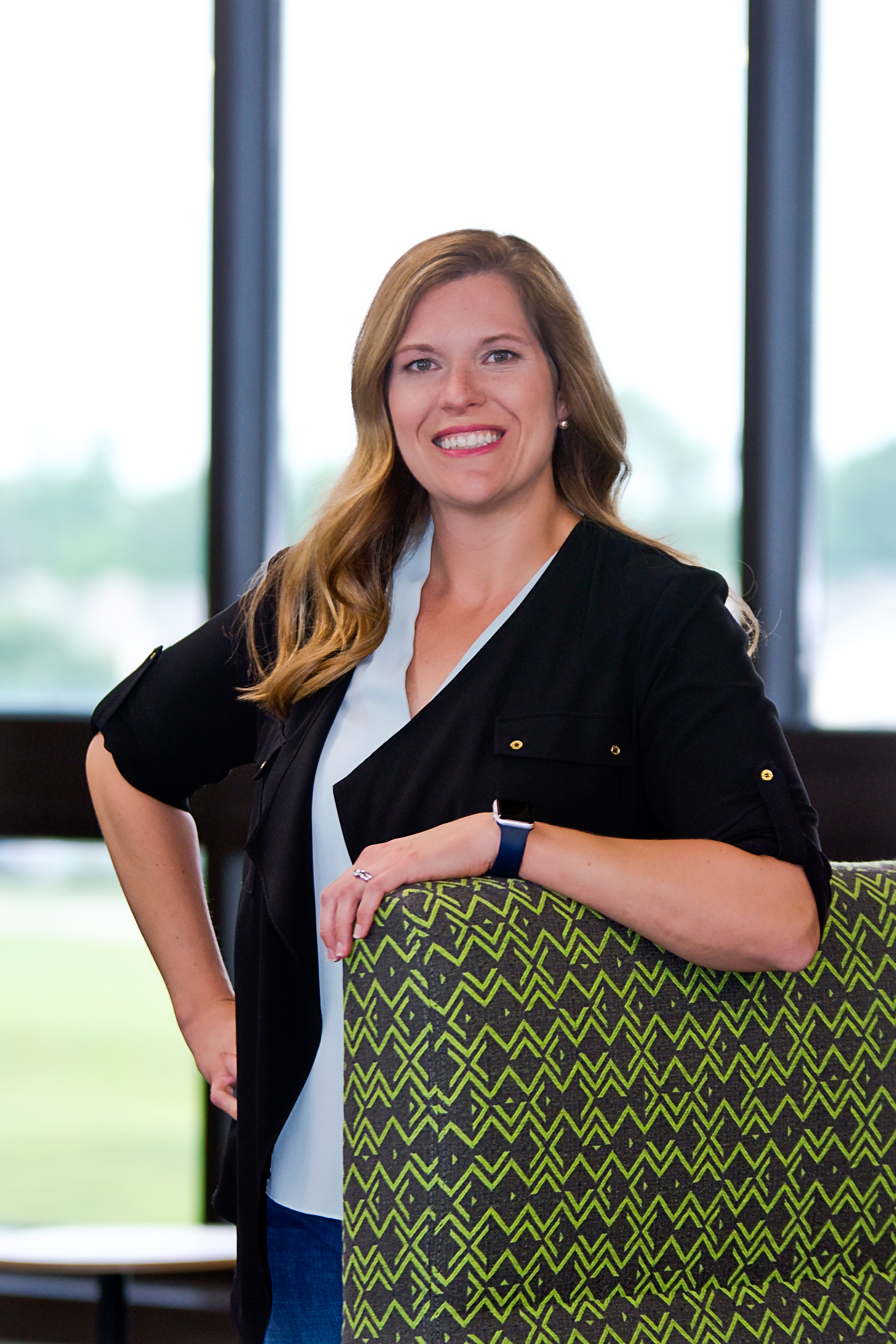 Anna Workman, posing by leaning with one elbow on a green chair.